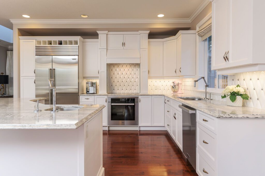 Modern white kitchen with stainless steel appliances.