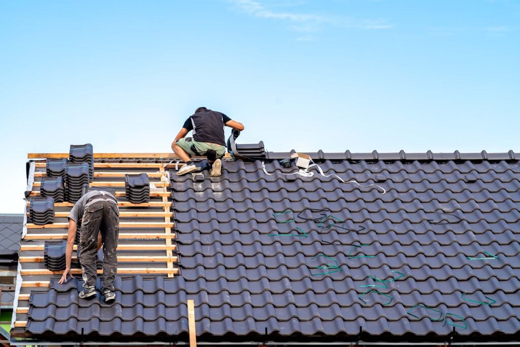 Workers installing tiles on a roof.
